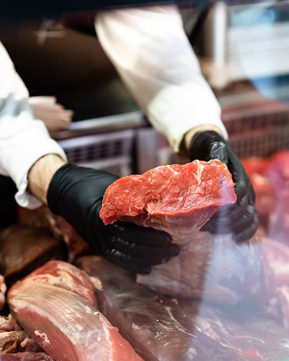 Macelleria e salumeria da Luca  B.R. CARNI SAS a Cepagatti PE (Pescara) - Macellaio che taglia la carne cruda in una macelleria.